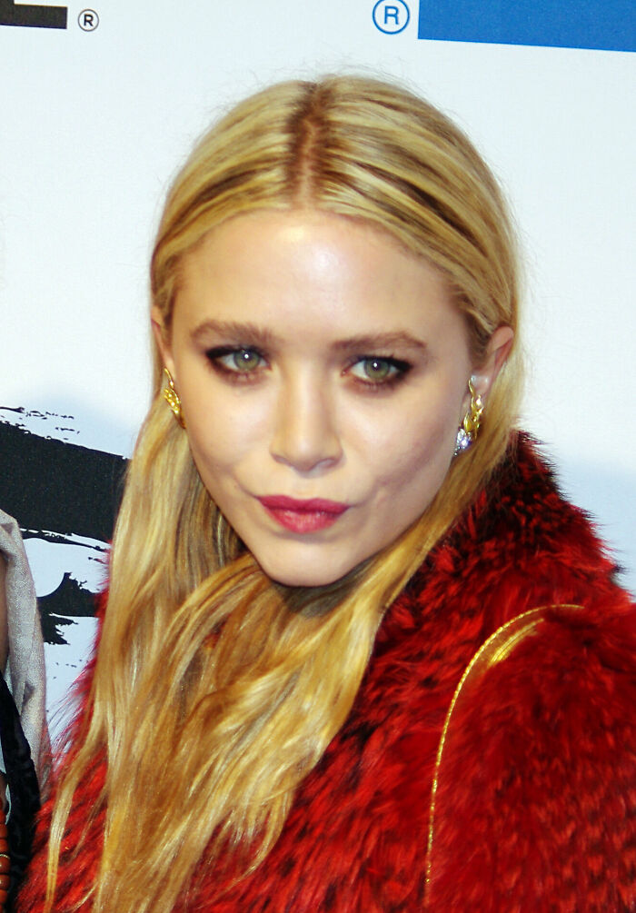 Close-up portrait of Mary-Kate Olsen wearing a red fur coat and gold earrings