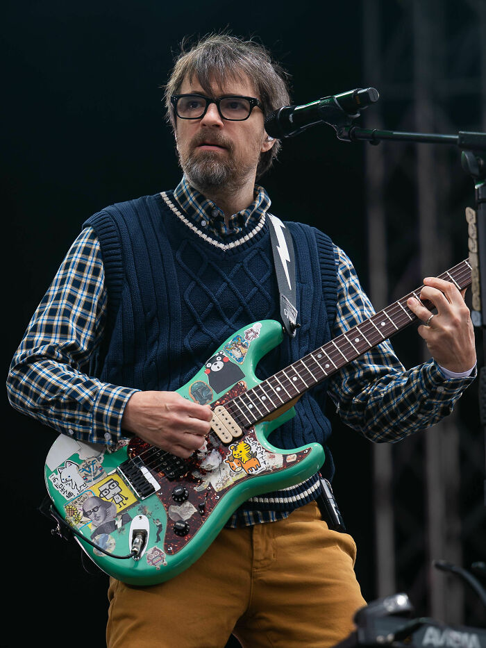 Rivers Cuomo playing electric guitar on stage during a live performance