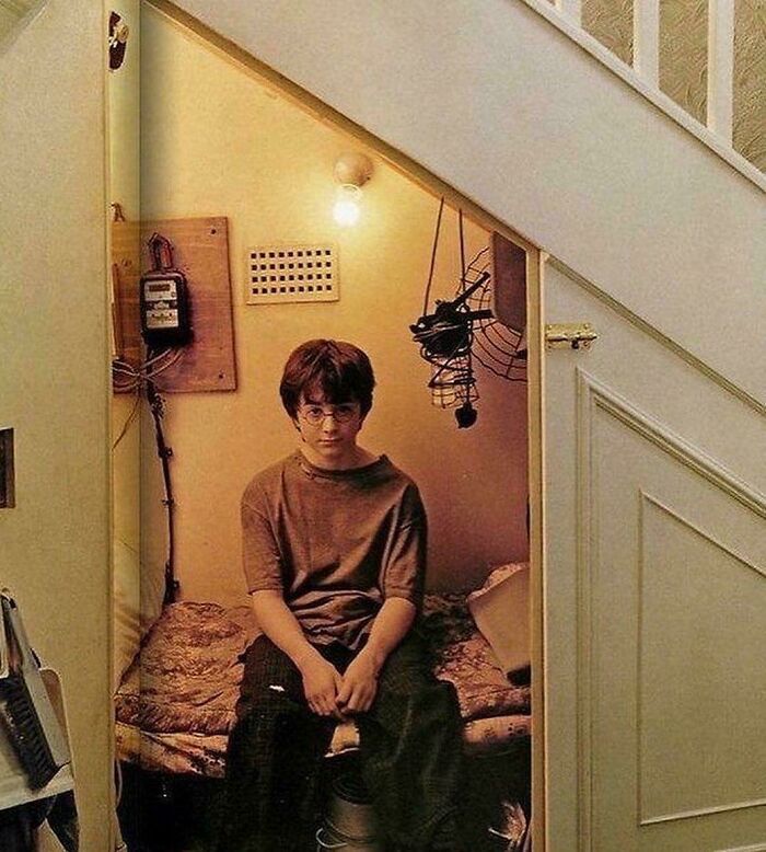 Harry Potter sitting in a small, cluttered cupboard under the stairs, showcasing nonsensical movie details.