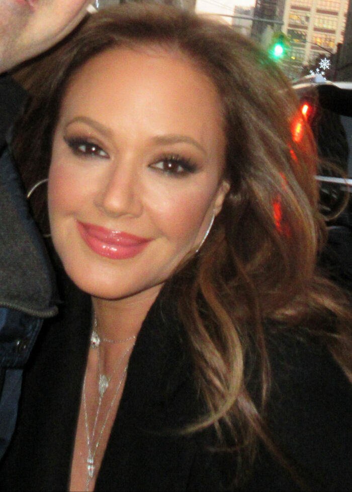 Close-up portrait of Leah Remini smiling outdoors with city lights in the background
