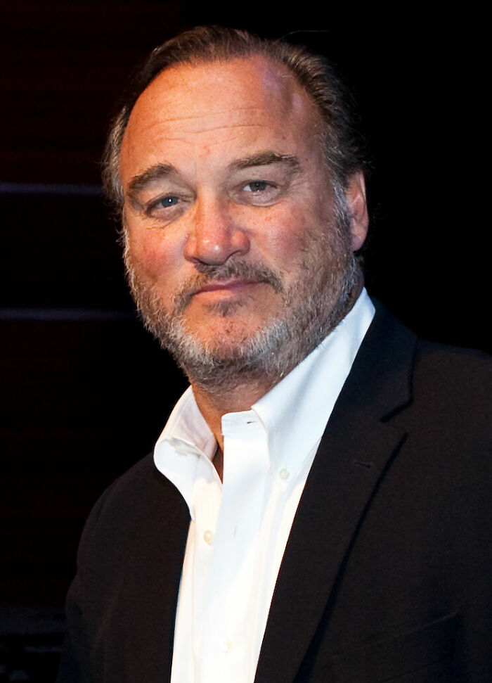 Close-up portrait of Jim Belushi in a black jacket and white shirt