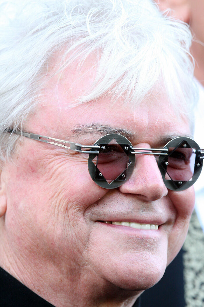 Close-up of Russell Hitchcock wearing unique geometric sunglasses smiling outdoors