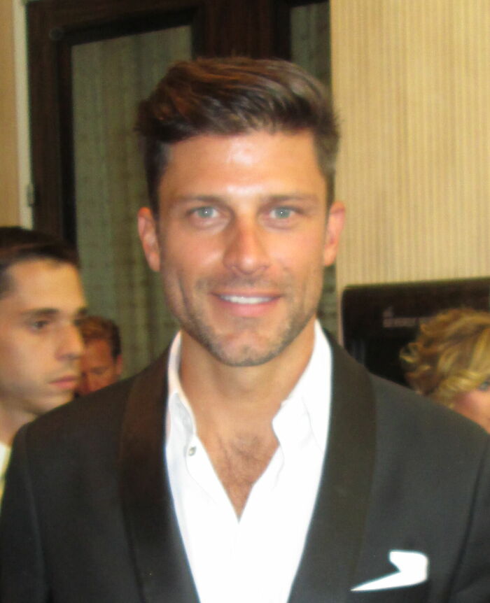 Greg Vaughan posing at an event with a black blazer and white shirt, highlighting his career