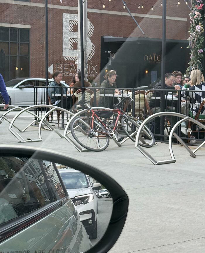 Urban bike rack design near a restaurant with people dining outside