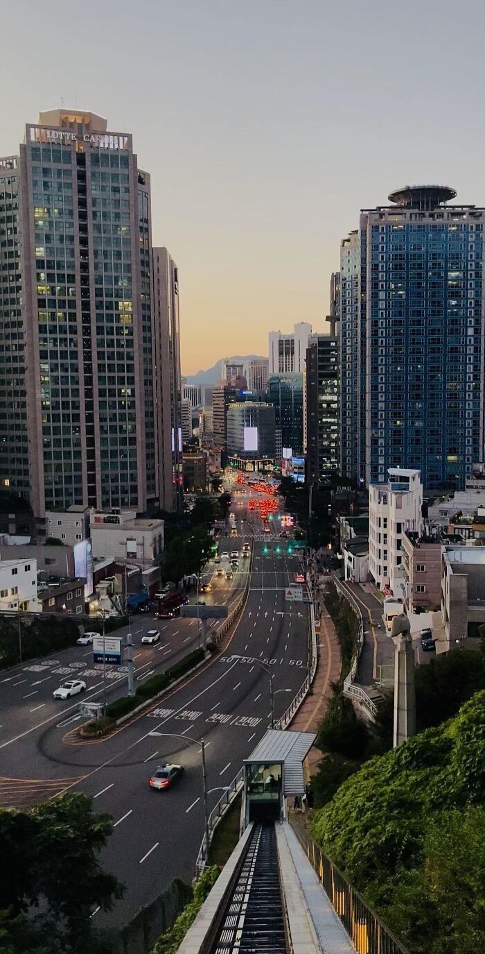 Cityscape at dusk with high-rise buildings and busy street in aesthetic photo