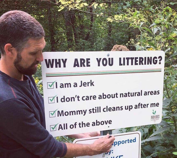 A man holding a funny sign in the wild asking, Why are you littering? with sarcastic options.