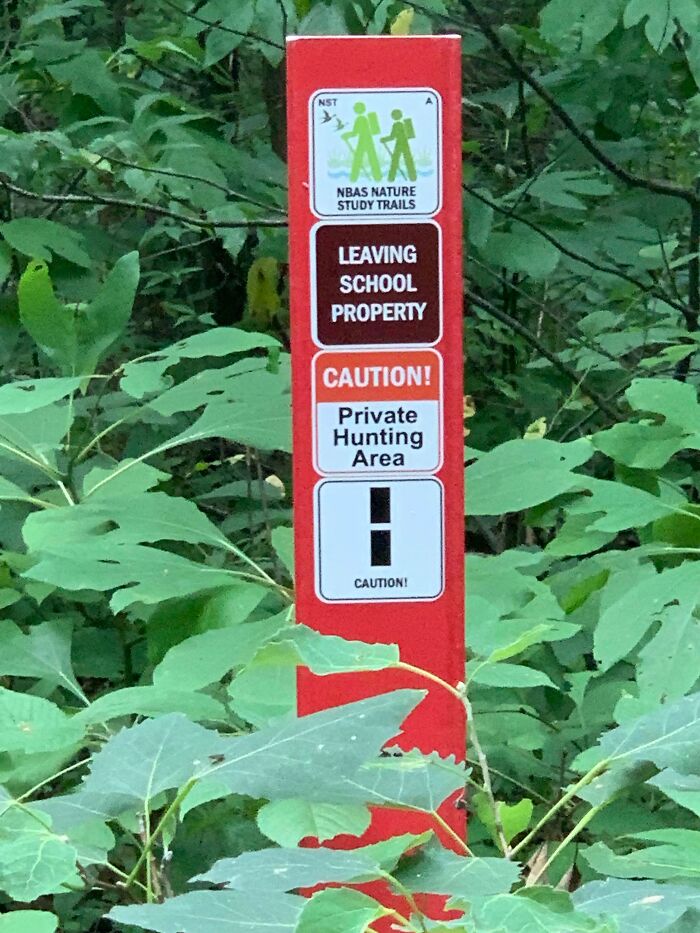 Funny signs in the wild: A red sign in foliage states LEAVING SCHOOL PROPERTY and Private Hunting Area.