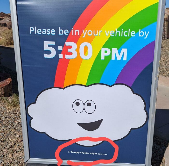 A funny sign in the wild with a rainbow and cloud warns to be in your vehicle by 5:30 PM or hungry coyotes might eat you.