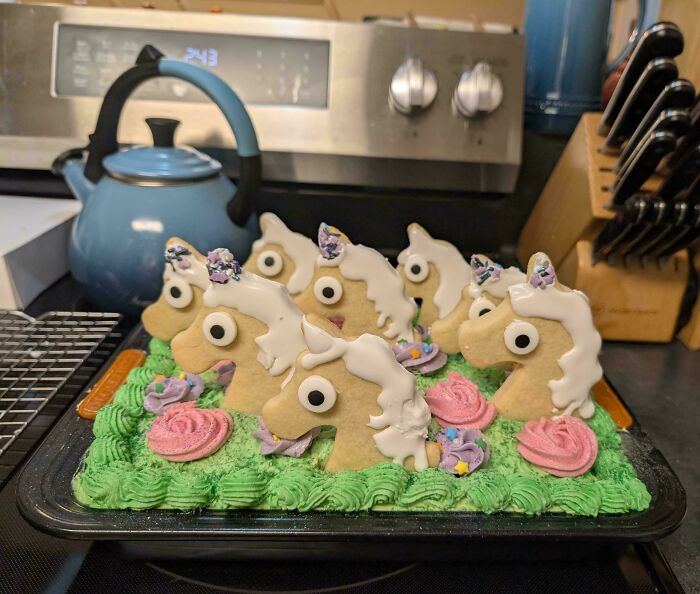 Unicorn cookies with colorful frosting on a green cake, showcasing creative and delicious treats from bakers.