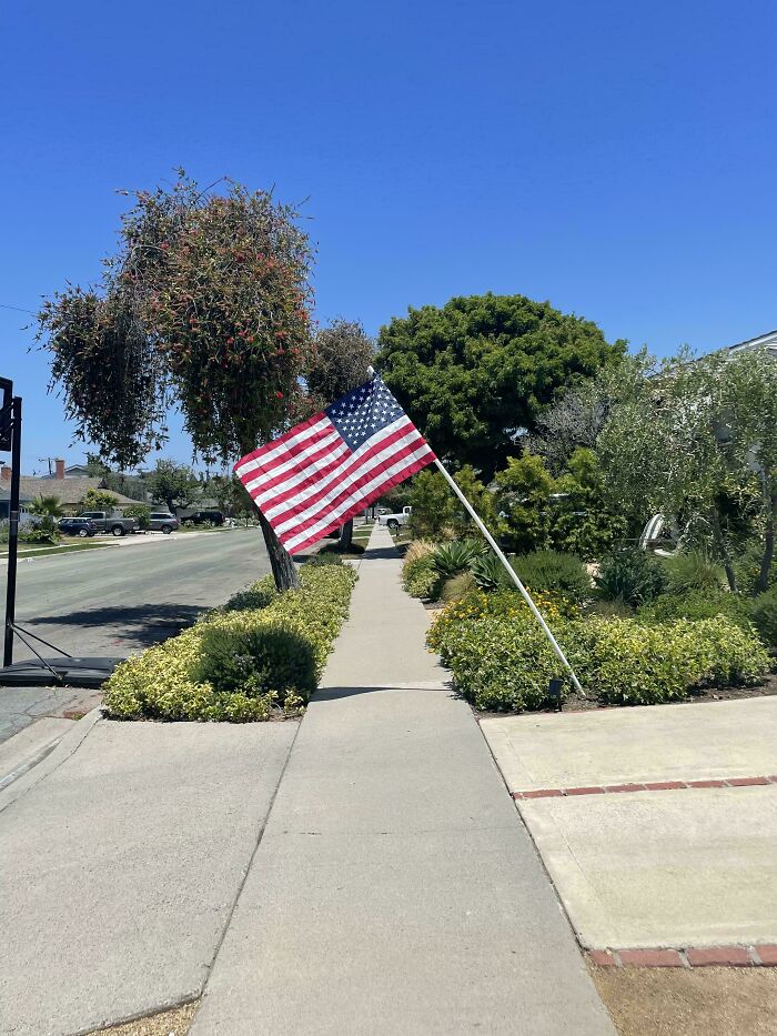 American flag displayed on sidewalk in sunny residential neighborhood