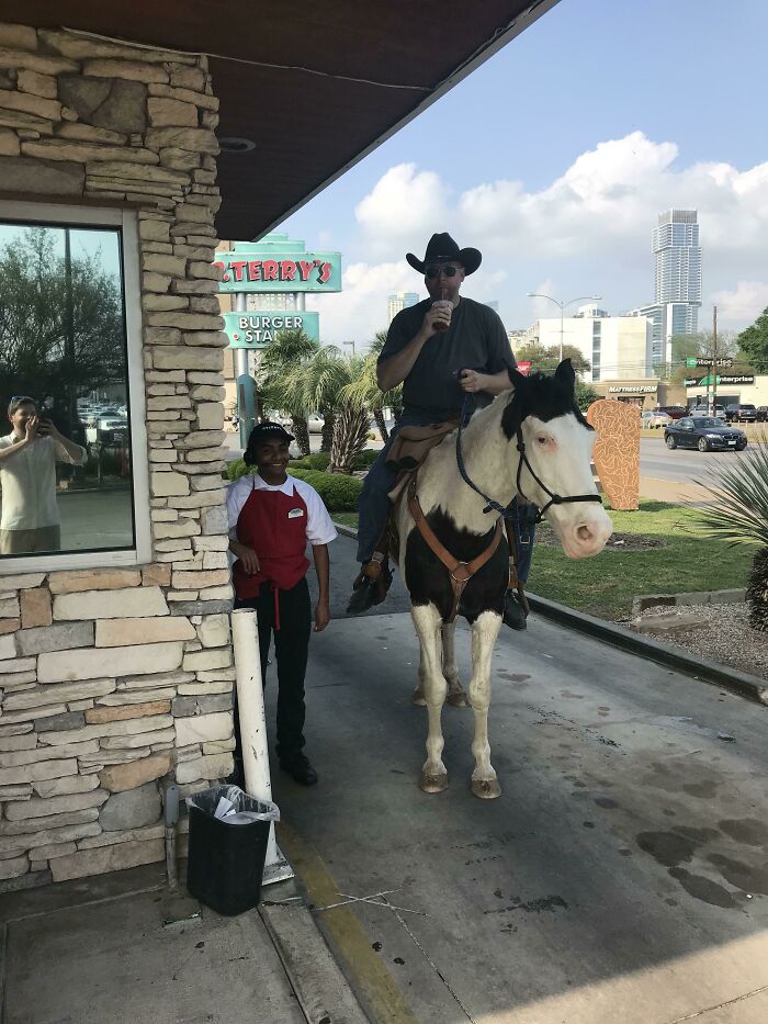 Man on horse orders drink at American burger stand with employee nearby