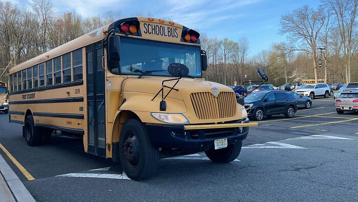 Yellow American school bus parked in a large parking lot on a clear day