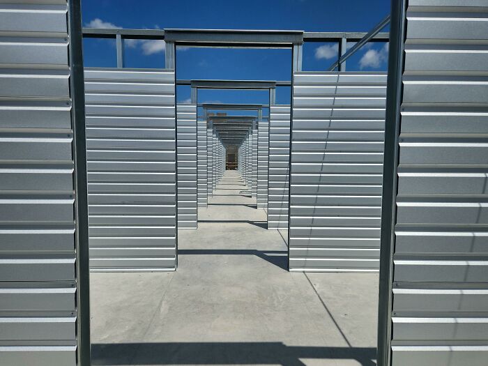 Unsettling liminal space with a repetitive series of metal structures extending into the distance under a blue sky.