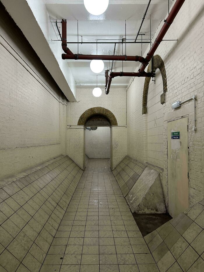 An eerie, tiled underground passage with exposed pipes, characteristic of a deeply unsettling liminal space.