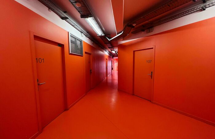 A long, bright orange hallway with numbered doors, an unsettling liminal space.