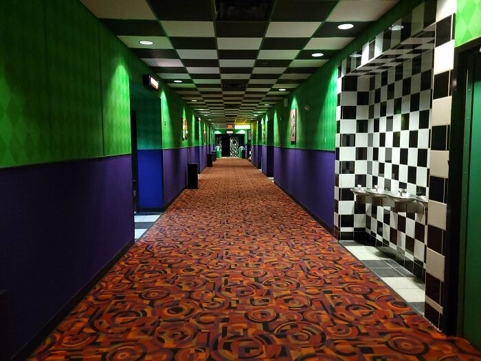 A long, colorful hallway with checkered ceiling and patterned carpet, an unsettling liminal space.