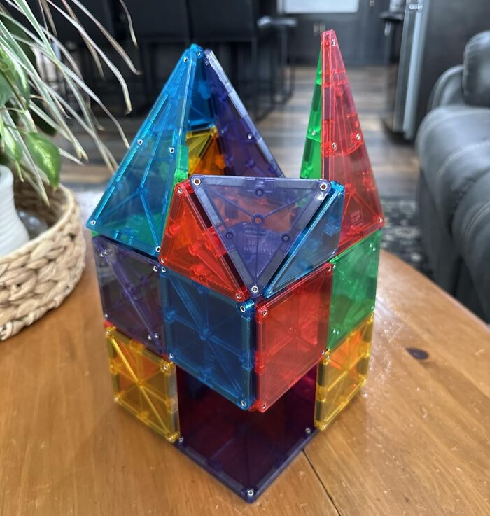 Colorful magnetic building tiles forming a house structure on a wooden table. Shop early Prime Day Deals on popular toys.