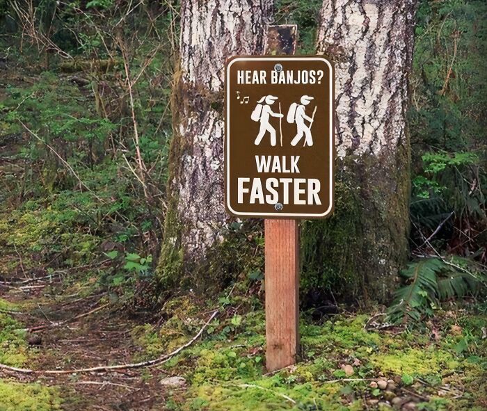 A funny sign on a trail that reads Hear Banjos? Walk Faster, with images of hikers.