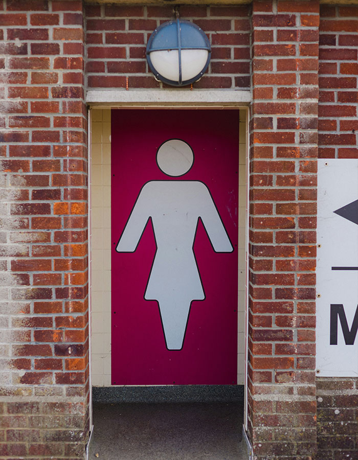 Entrance to women's restroom with large female symbol on maroon door Entrance to women's restroom with large female symbol on maroon door