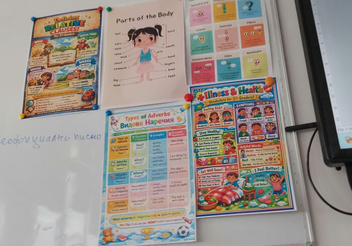 A white board with several educational posters, including topics like relative clauses, parts of the body, and illness & health, indicating toxic teachers.