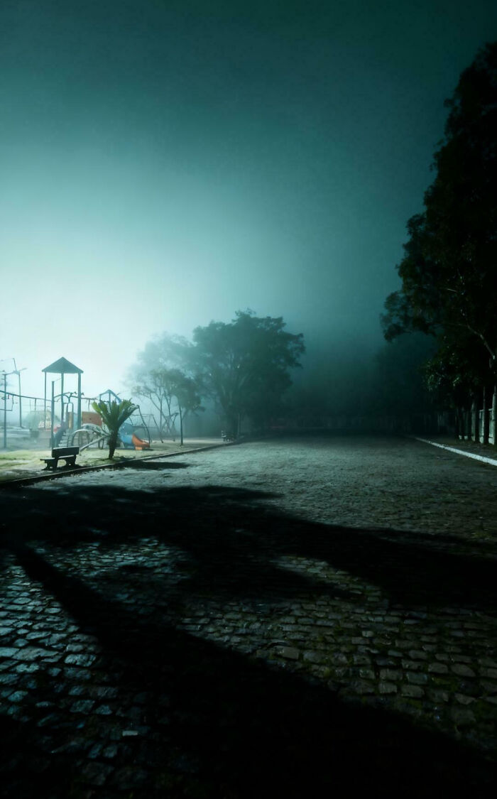 An unsettling foggy night scene of a deserted liminal spaces playground, emphasizing a mysterious atmosphere.