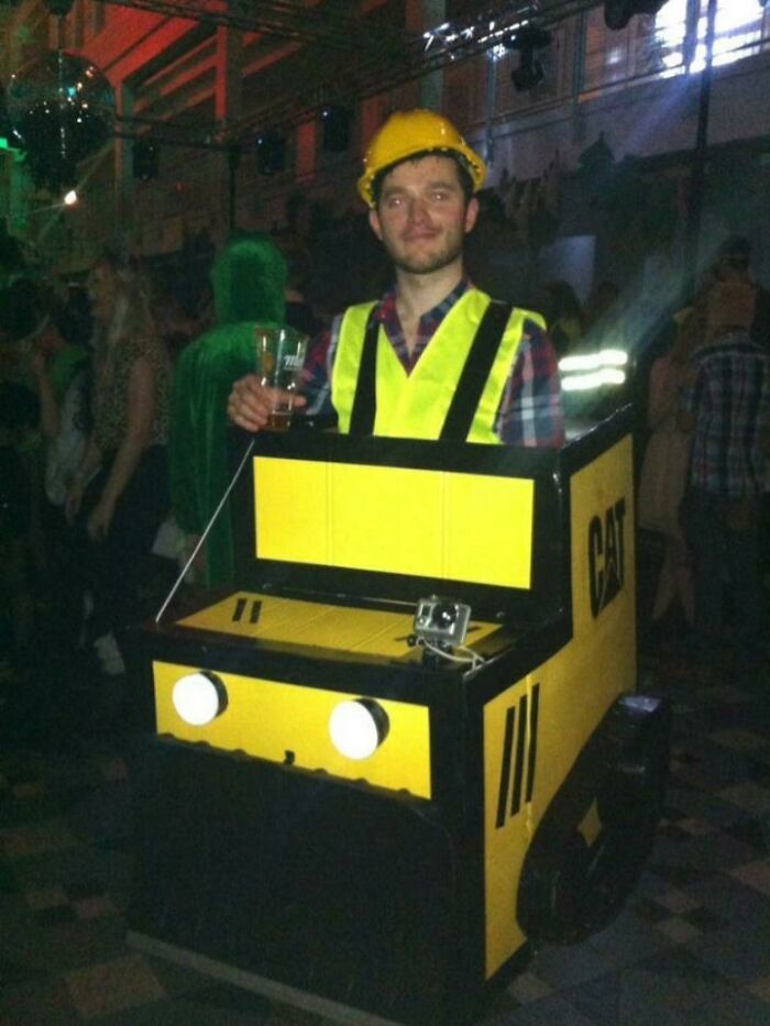 A Mad Lad dressed as a construction vehicle at a party, holding a drink.