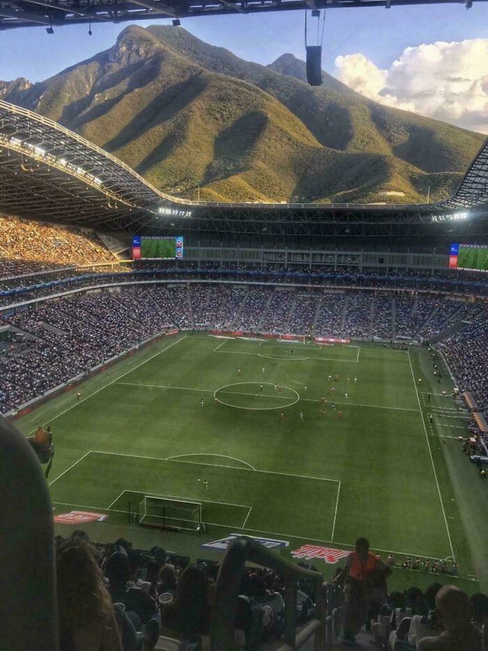 An expansive view of a soccer stadium with a large mountain backdrop, an interesting post.