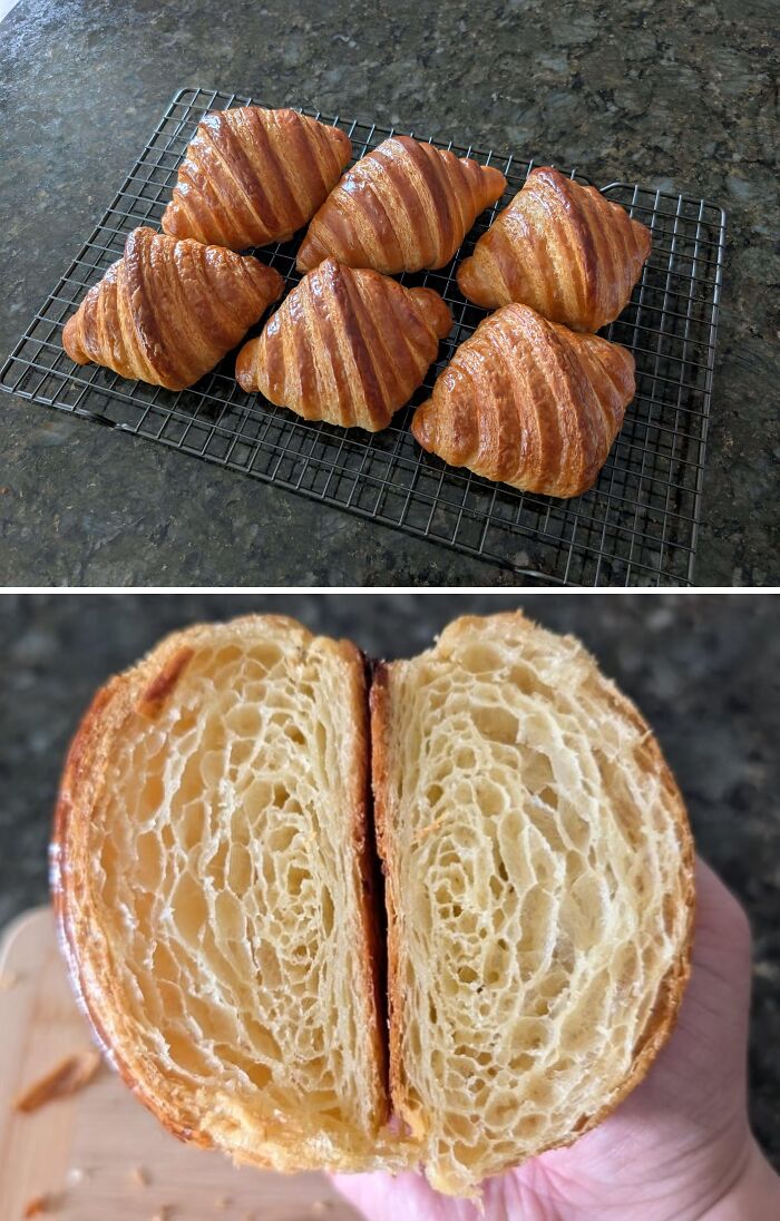 Golden croissants cooling on a wire rack on a dark countertop