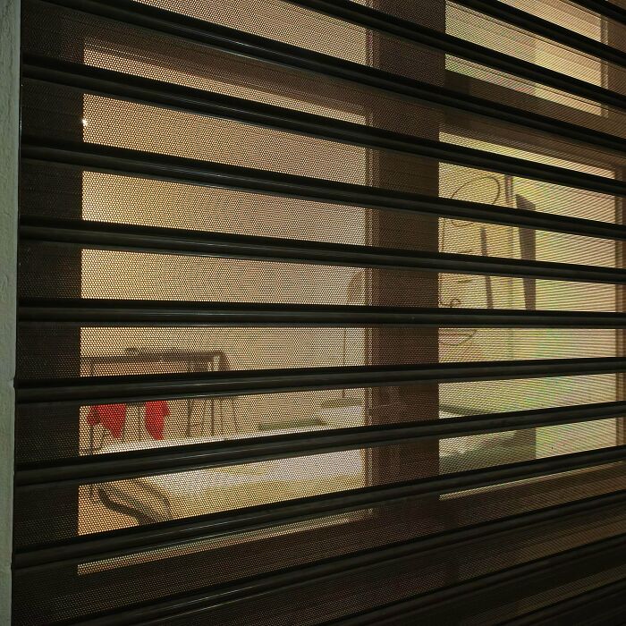 An unhinged real estate listing shows a view through a perforated metal security gate.