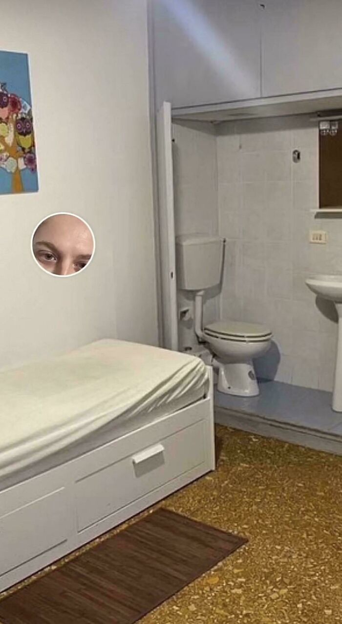 A small bedroom with a bed directly adjacent to a toilet and sink, from unhinged real estate listings.
