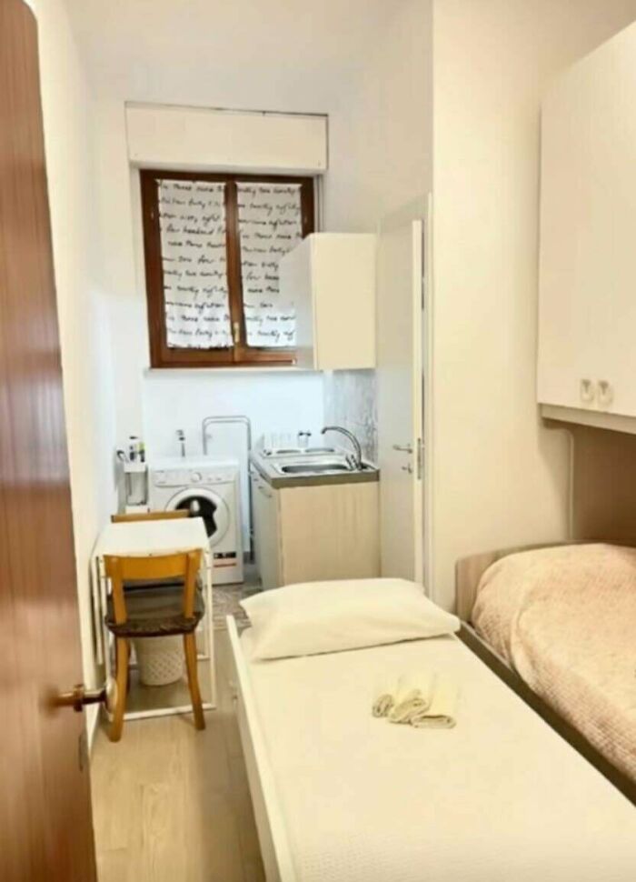 A cramped and unhinged real estate listing showing a bed, washing machine, and sink in one small room.