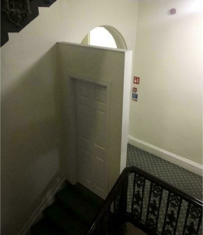 An odd real estate listing featuring a small, short door built into a wall next to a staircase, appearing out of place.