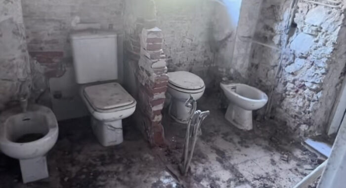 An unhinged real estate listing with four toilets and bidets in a single, partially demolished, grimy bathroom.