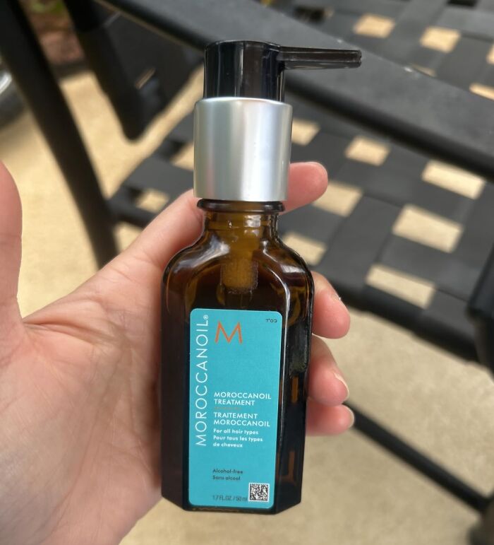 A hand holds a small bottle of Moroccan oil treatment, one of the best Prime Day deals for hair care.