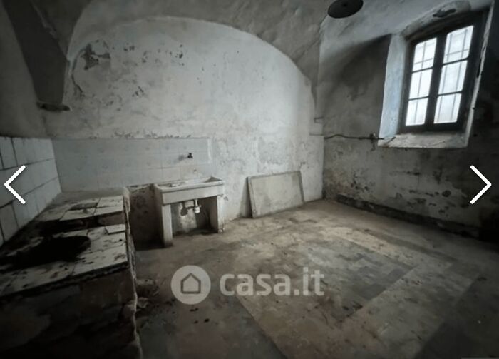 A very run-down and unhinged real estate listing, featuring a dilapidated room with a single sink and dirty walls.