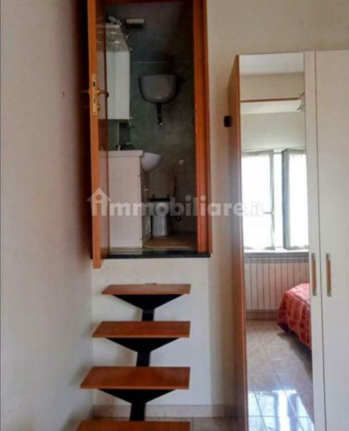 An unhinged real estate listing with a tiny bathroom above a steep set of wooden steps.