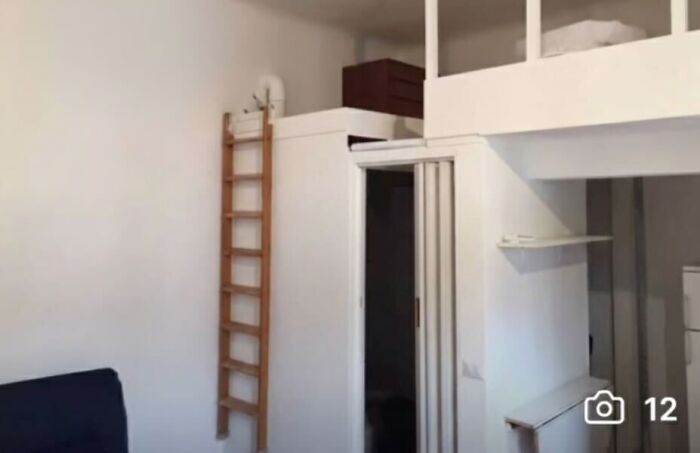 A small, unhinged real estate listing with a loft bed accessed by a wooden ladder.