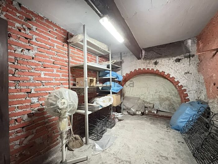Unhinged real estate listing: a dimly lit, unfinished basement with exposed brick walls, metal shelving, and various stored items.