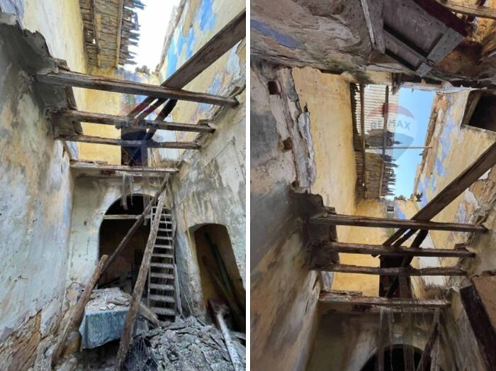 A dilapidated interior of unhinged real estate listings with exposed wooden beams and a collapsed ceiling, needing repair.