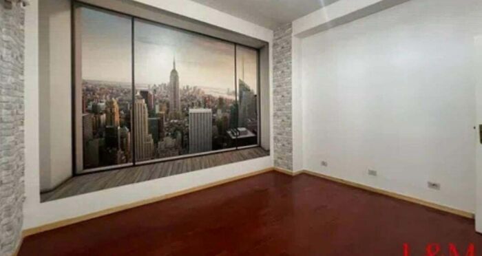 An empty room with a large window mural of a city skyline, part of an unhinged real estate listing.