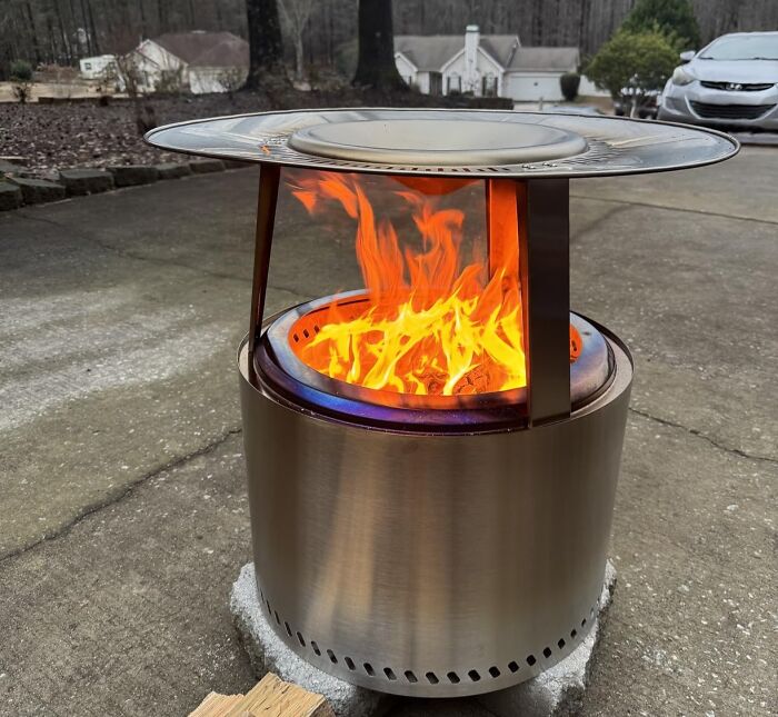 Prime Day outdoor and backyard essentials for summer, a stainless steel fire pit with a roaring fire on a patio.
