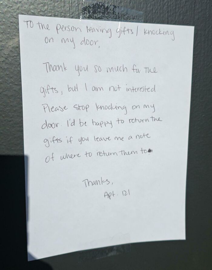 A funny neighbors note taped to a door, politely asking someone to stop leaving gifts and knocking.
