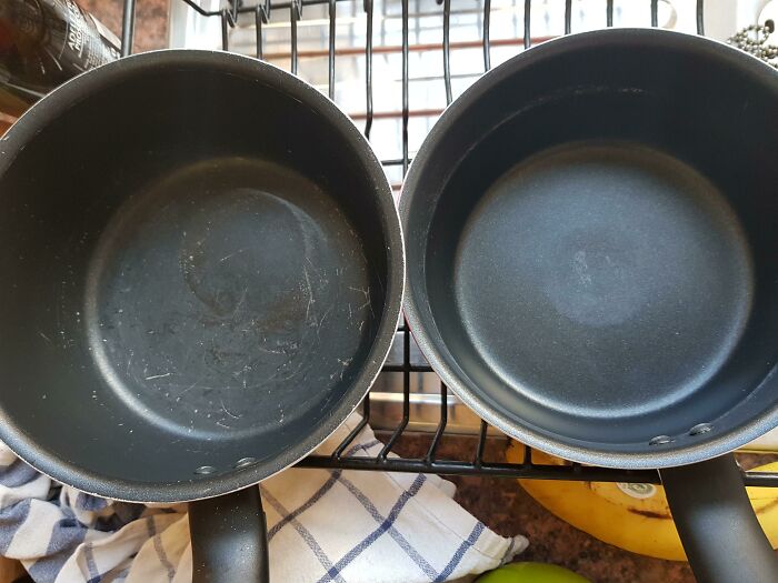 Two scratched pots on a drying rack, showing wear and tear, likely caused by a horrible roommate.