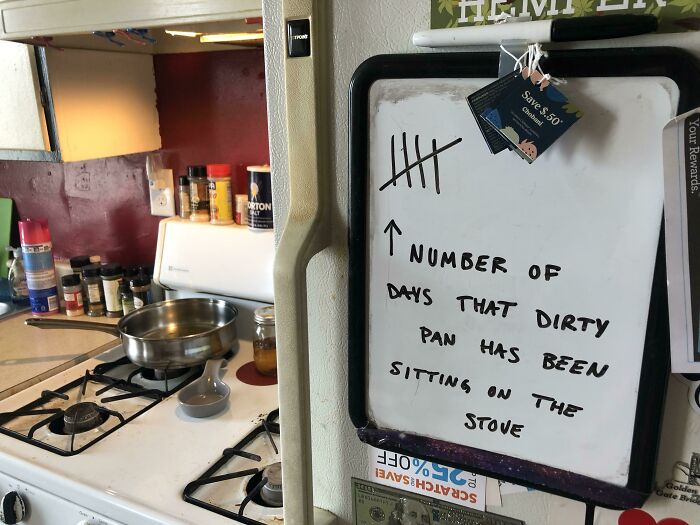 A whiteboard tallying days a dirty pan sits on the stove, a classic sign of horrible roommates.