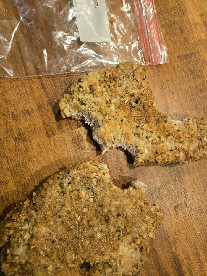 A close-up of two pieces of undercooked breaded meat, revealing a pinkish-purple interior, showcasing horrible roommates.