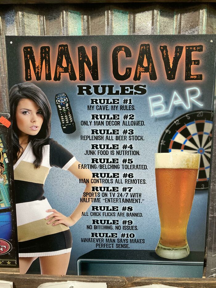 A woman posing next to a Man Cave Rules sign, representing toxic masculinity.