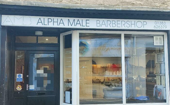 The storefront of a barbershop named Alpha Male Barbershop, representing toxic masculinity.