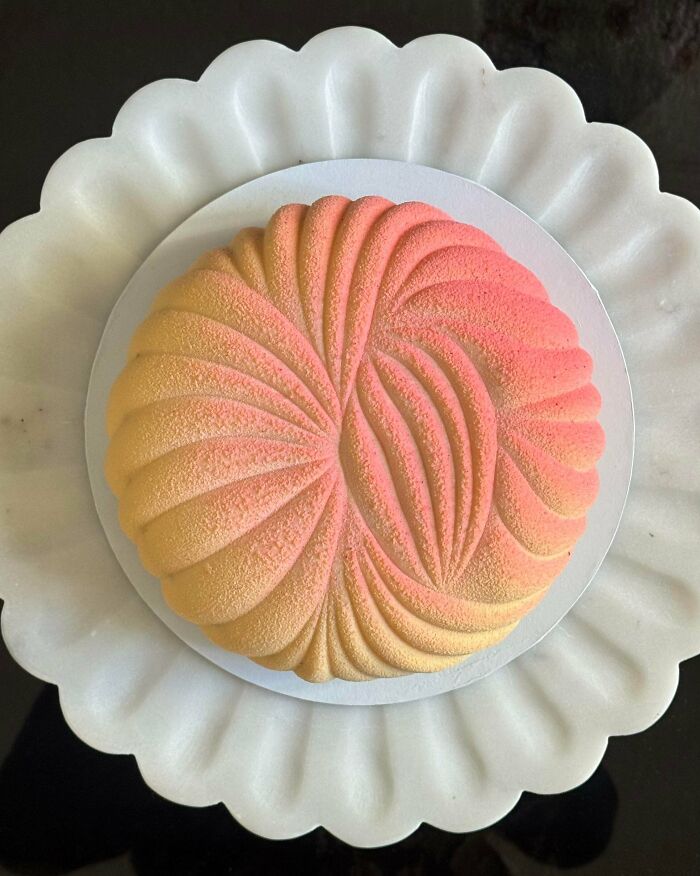 An amazing baker's treat: a beautiful round dessert with a textured, gradient design of yellow and pink.
