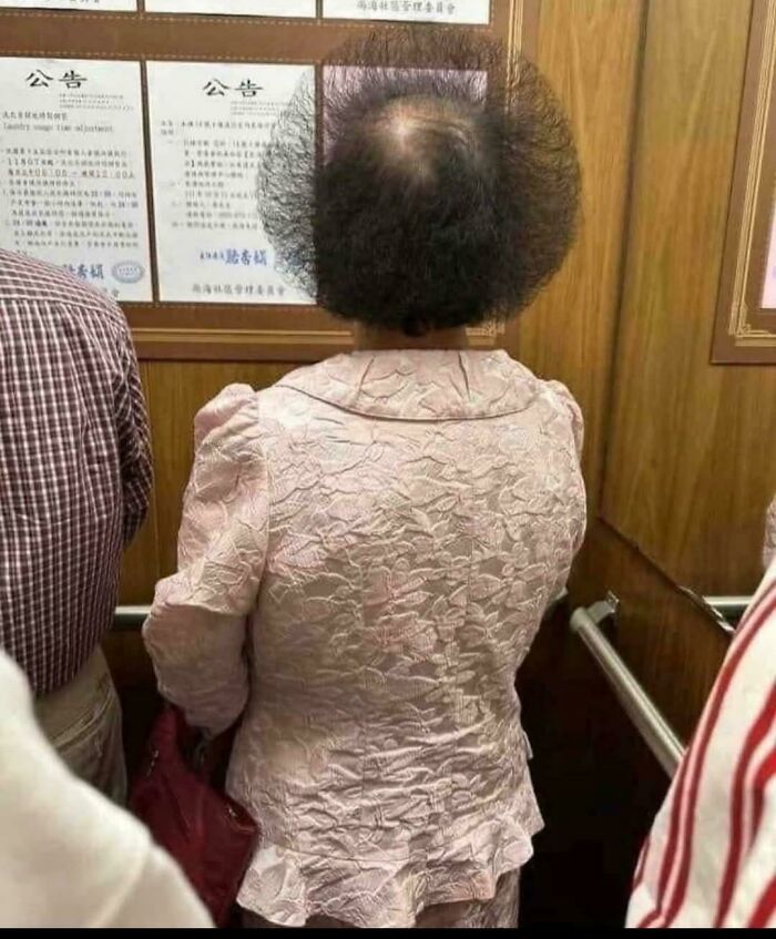 Woman with unfortunate haircuts, showcasing a highly uneven circular cut from behind in an elevator.