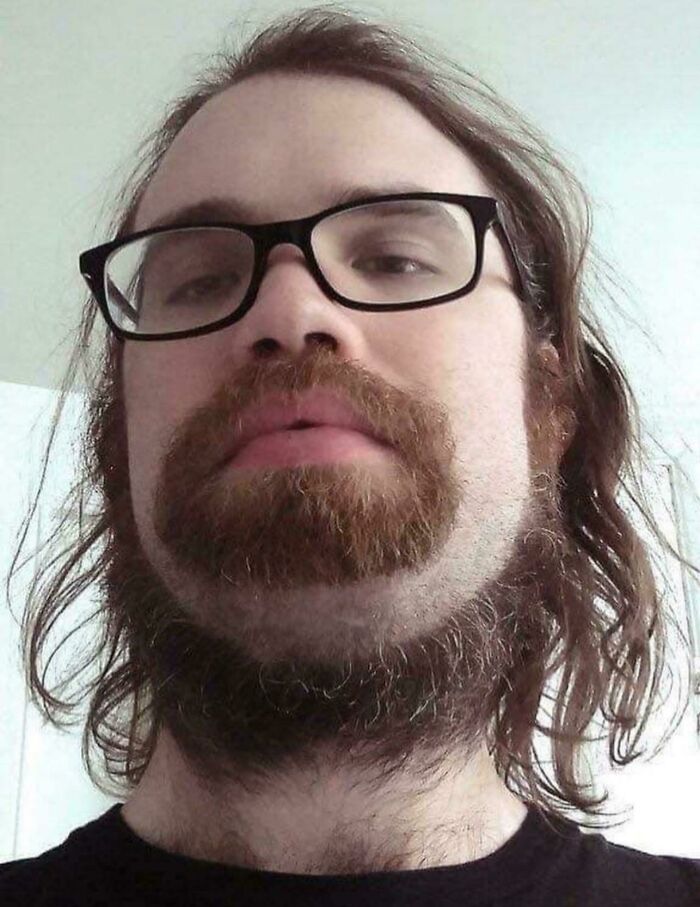 Man with unfortunate haircuts, featuring a long, unkempt style with a disconnected beard.